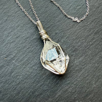 Necklace with a pendant featuring a clear gemstone on a dark gray background