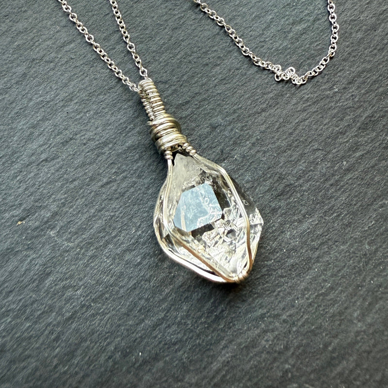 Necklace with a pendant featuring a clear gemstone on a dark gray background